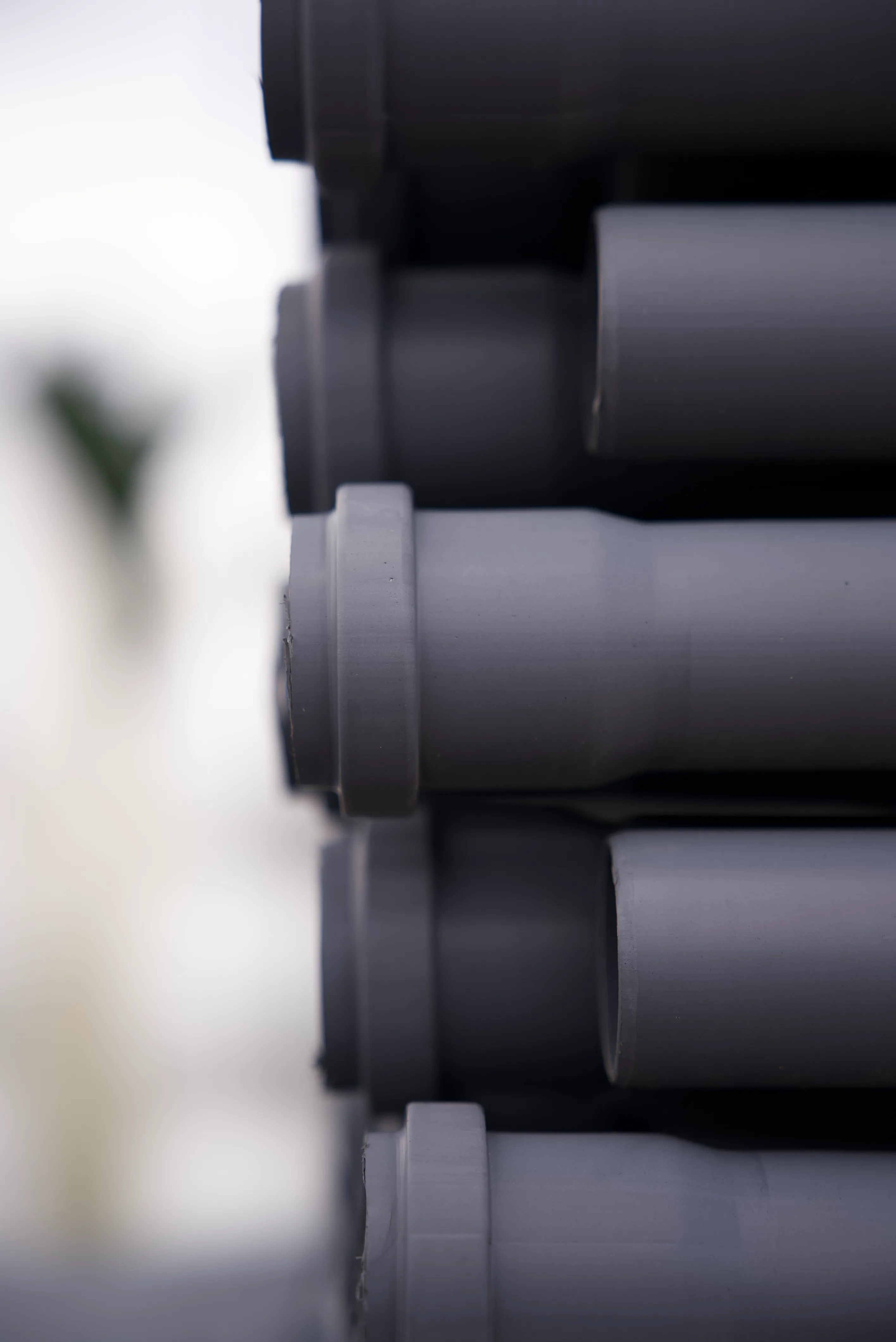 Szare rury kanalizacji wewnętrznej, ułożone pionowo w schludnym układzie.