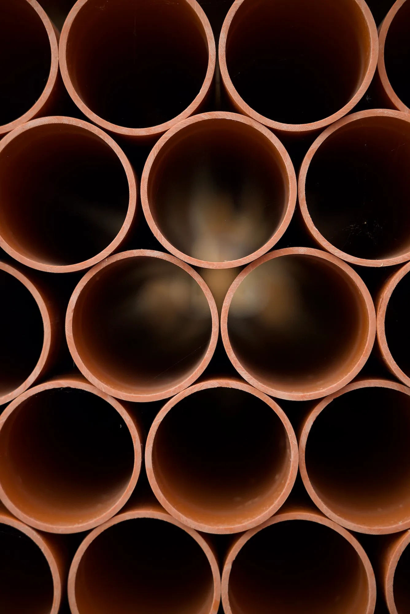 Rury kanalizacji zewnętrznej o ceglanym kolorze, widok przez środek rury.