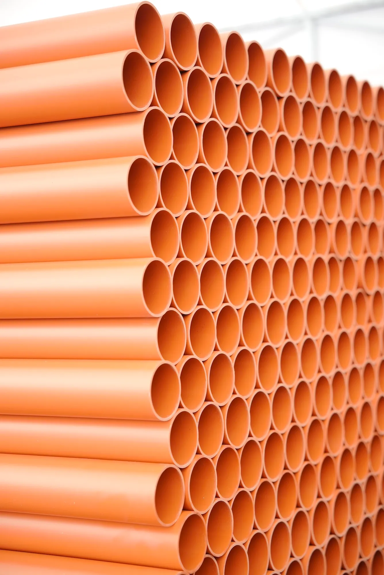 Rury kanalizacji zewnętrznej o ceglanym kolorze, ułożone poziomo w schludnym układzie.