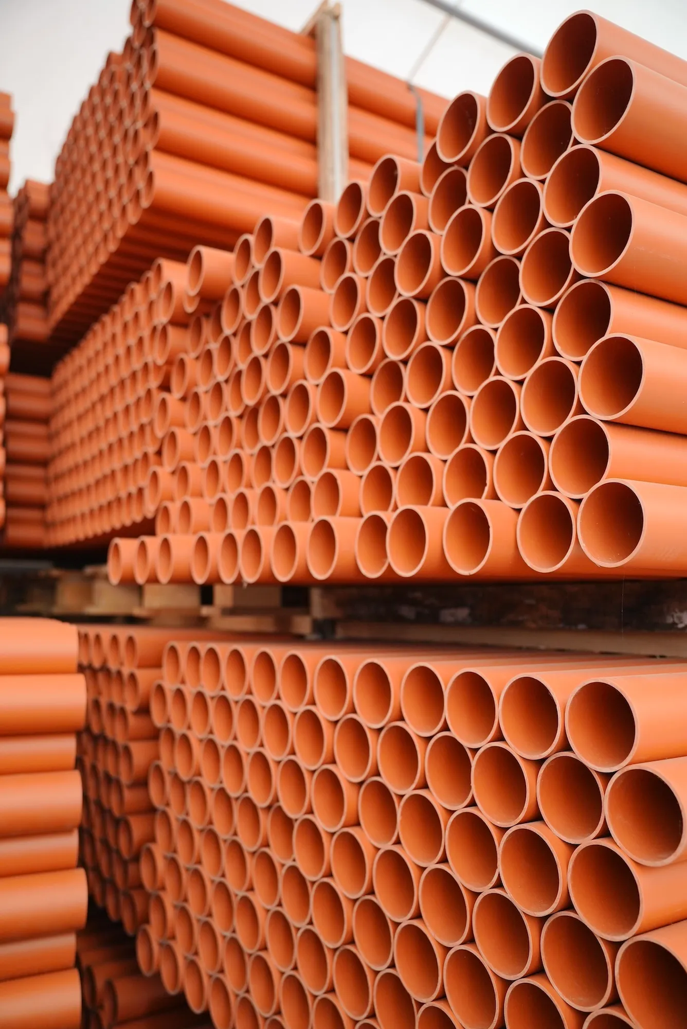 Rury kanalizacji zewnętrznej o ceglanym kolorze, ułożone poziomo w schludnym układzie.