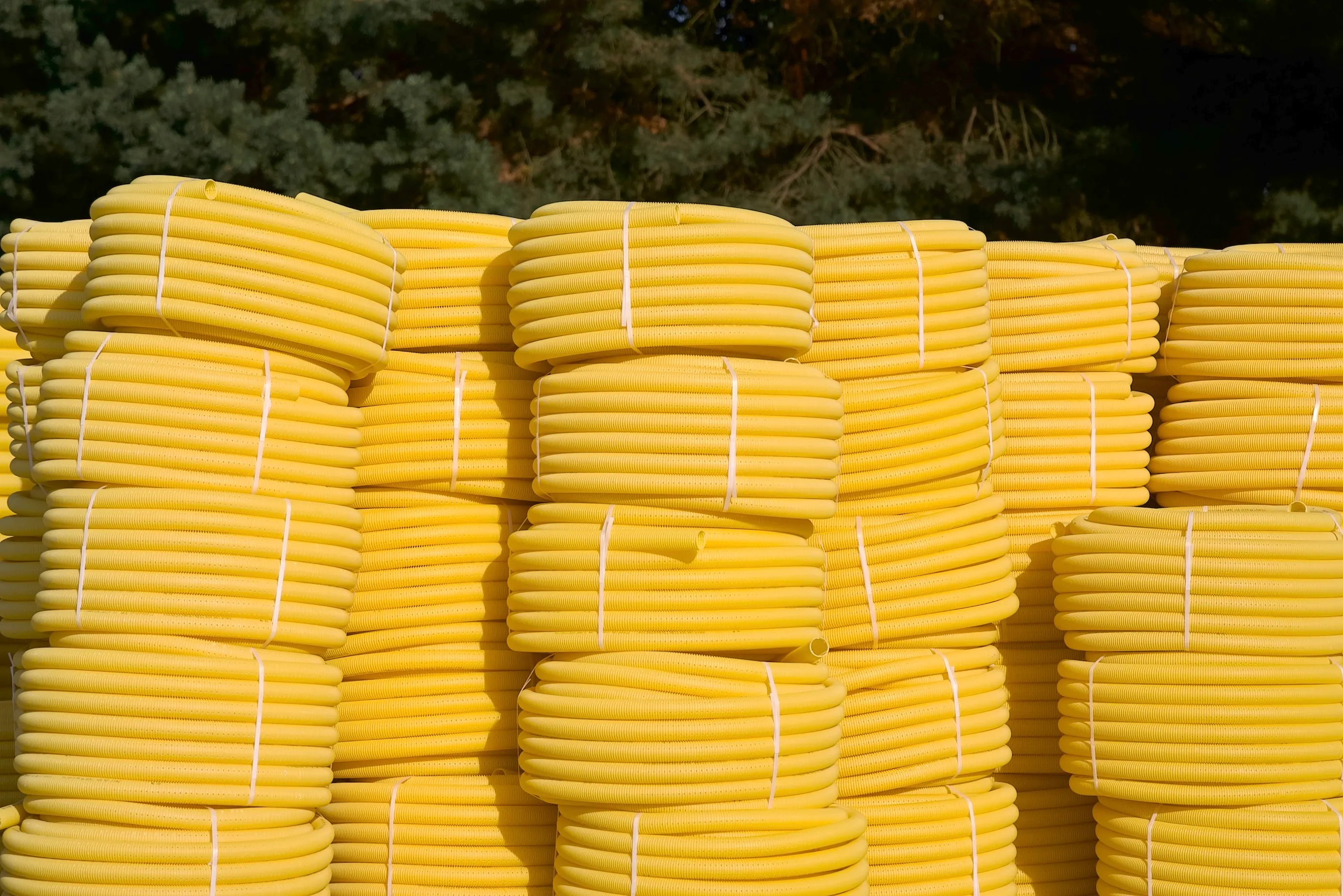 Zwoje żółtych rur drenażowych Drewplast prezentujące elastyczność i trwałość produktu do instalacji drenarskich.