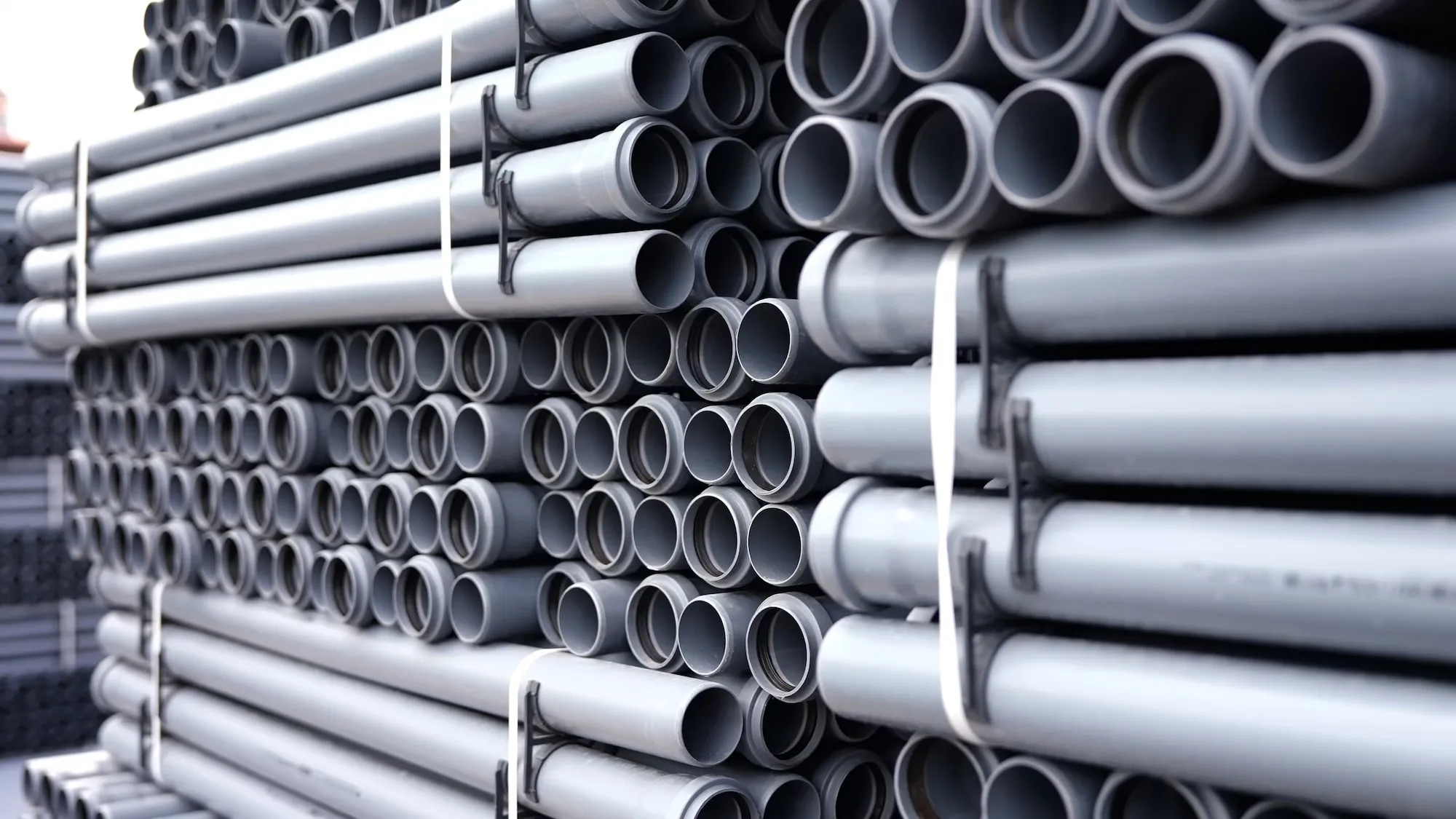 Szare rury kanalizacji wewnętrznej, ułożone poziomo w schludnym układzie.