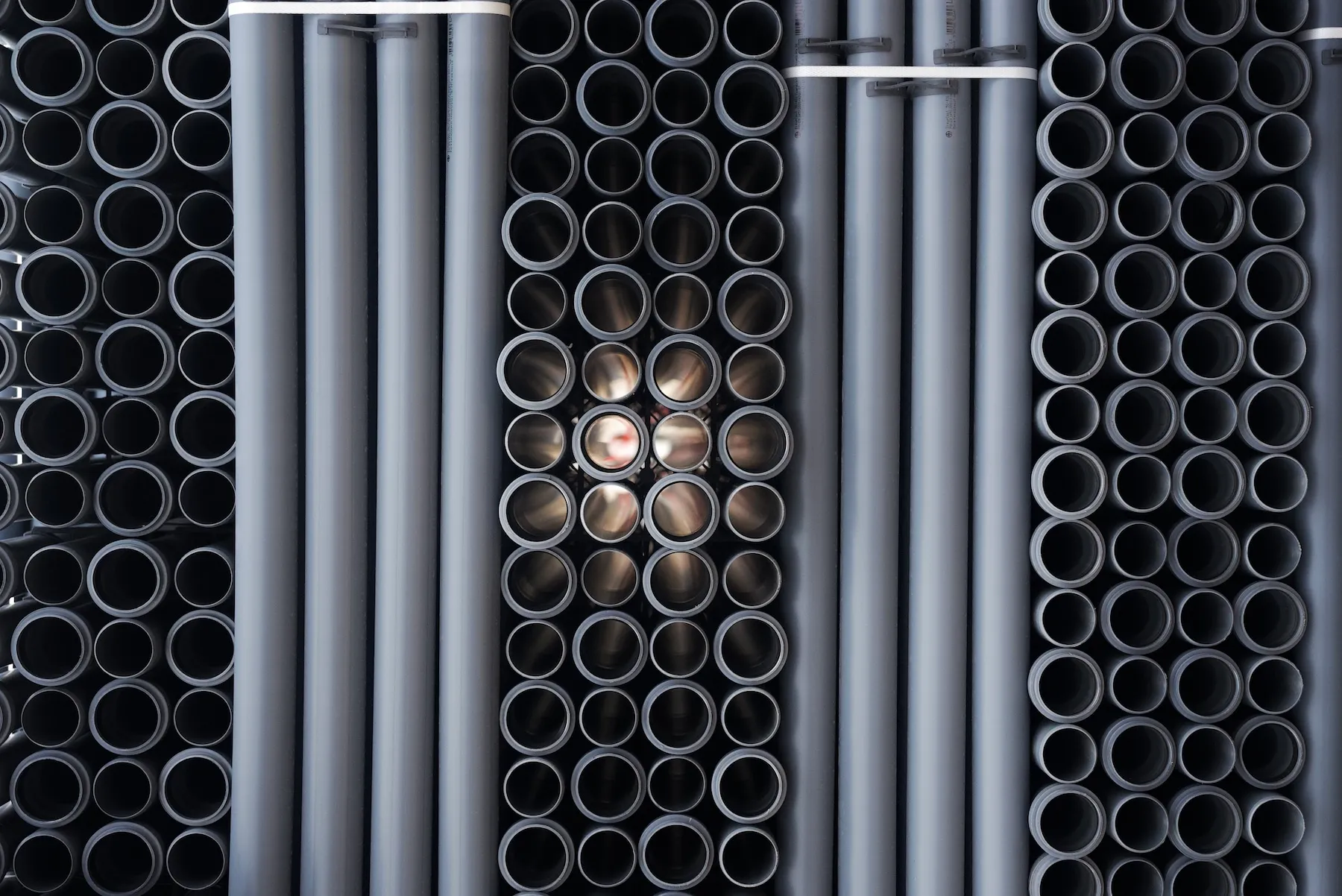 Szare rury kanalizacji wewnętrznej, starannie ułożone w miejscu składowania.